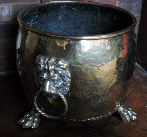 A fine brass log bin with large lion masks with ring handles standing on lion paw feet